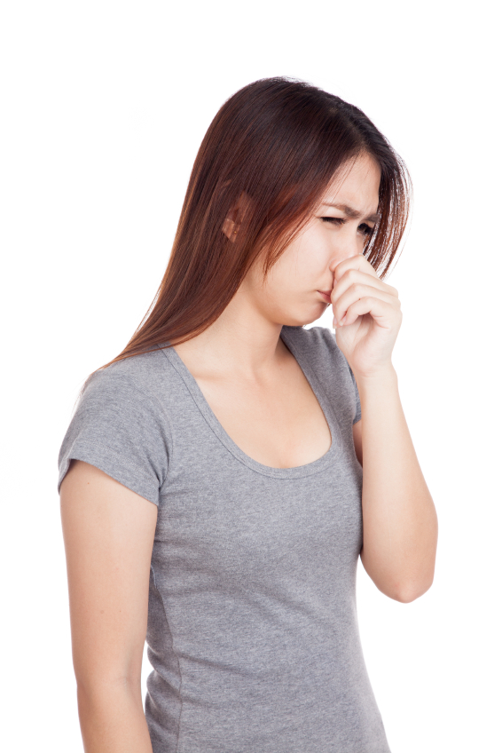 年轻的亚洲女子因为难闻的气味而捂着鼻子