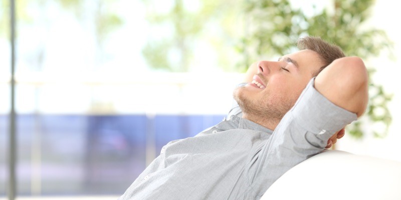 男人坐在沙发上，向后靠，深深地吸了一口气