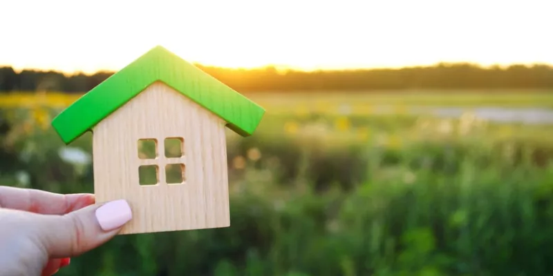 女士拿着木制的房子在领域的背景下